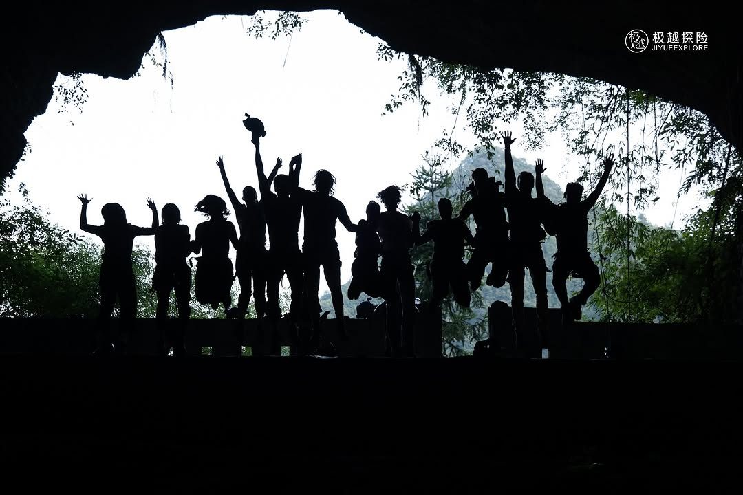 A group silhouetted at the mouth of a cave